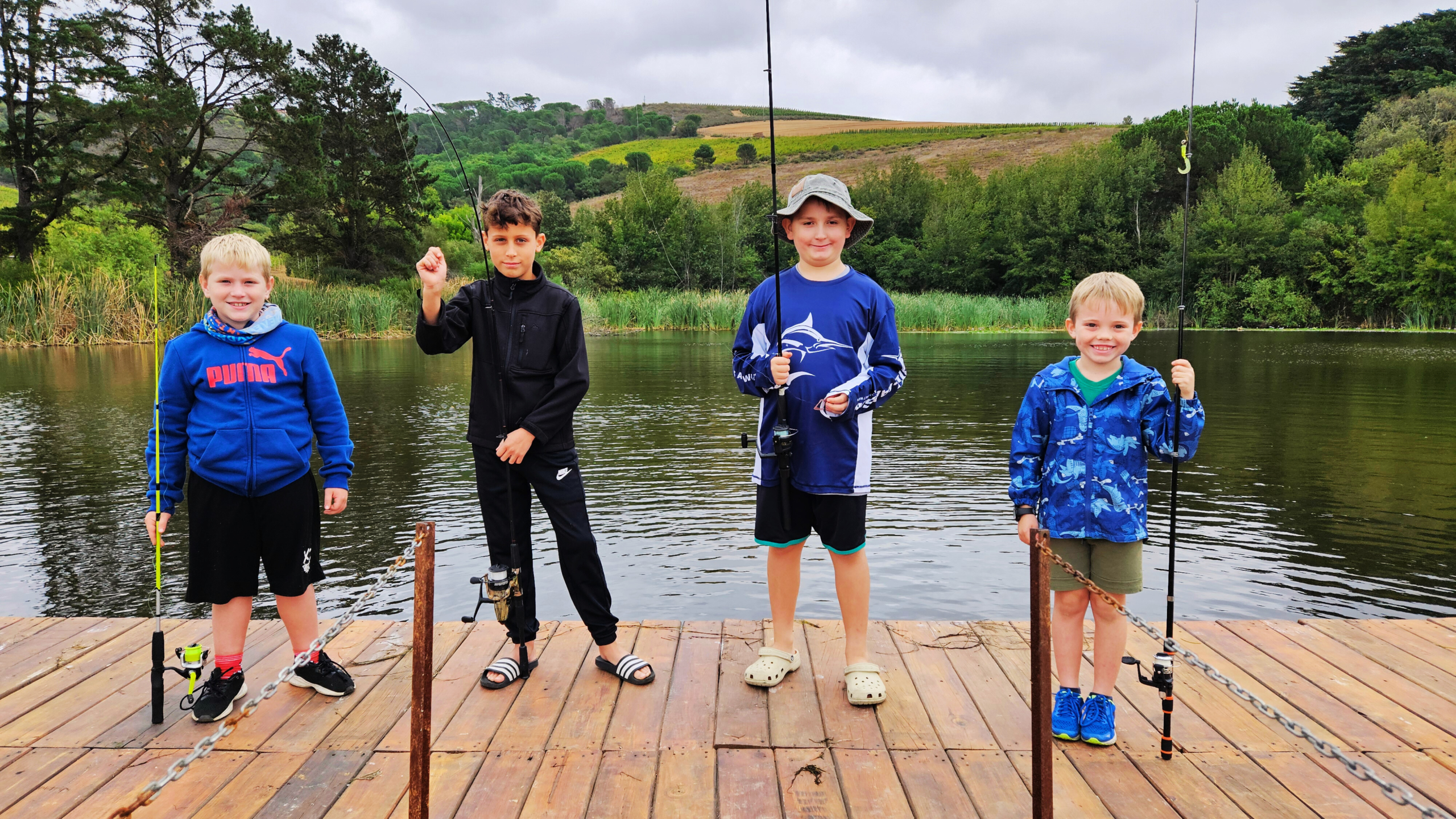 Four young boys holding fishing rods on a wooden jetty at Kanu during the Catch Club session on 29 March 2025